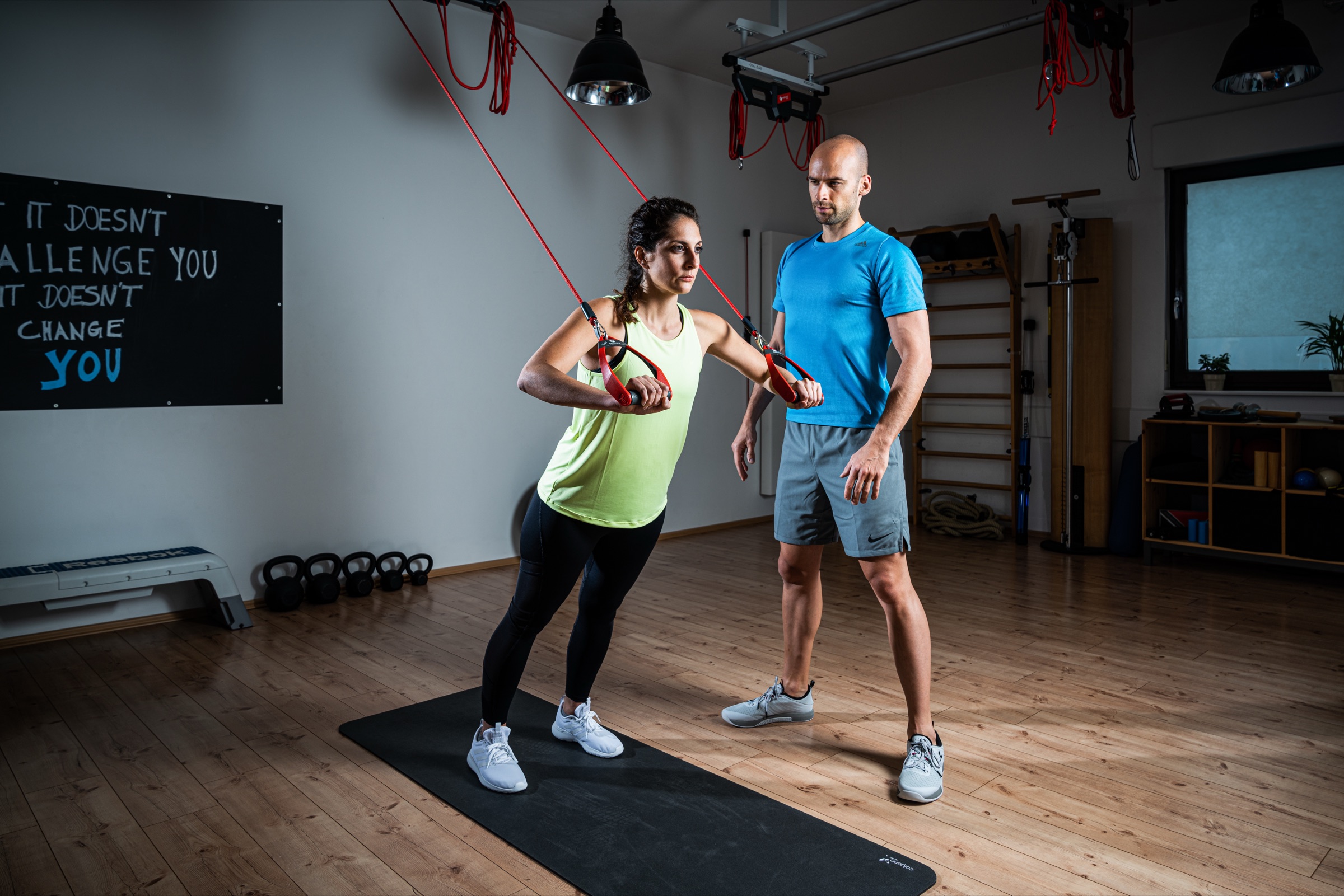 An instructor coaching a participant through a supported Redcord exercise during a course